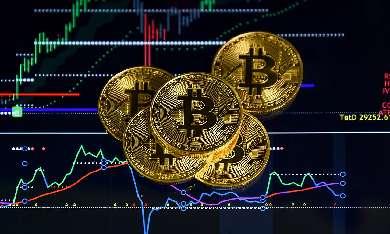 Gold souvenir Bitcoin tokens in front of a chart screen